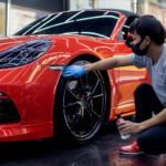 Technician wearing gloves manually inspecting a premium car’s tire at Exclusive Car Care Abu Dhabi.
