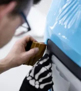 Professional technician applying car wrapping film in Abu Dhabi for vehicle paint protection.